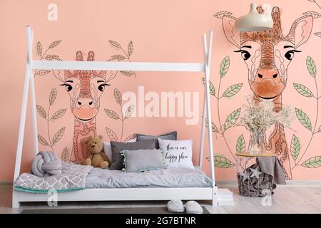 Interno della moderna camera per bambini con comodo letto e quadri di  graziosa giraffa sulla parete Foto stock - Alamy