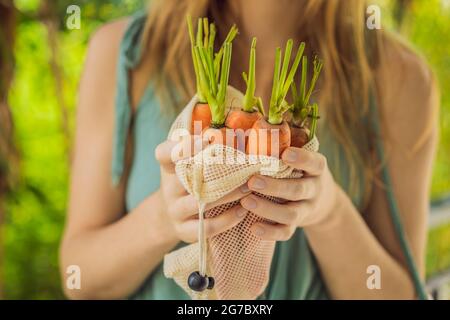 Carota in una borsa riutilizzabile nelle mani di una giovane donna. Concetto di zero sprechi Foto Stock