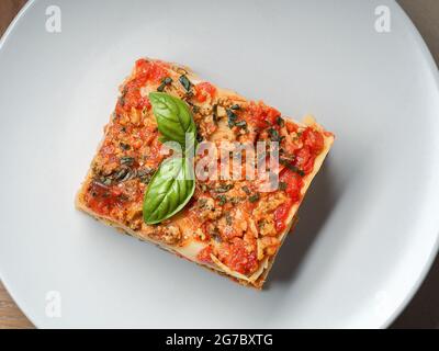 Pezzo di lasagna su piatto bianco primo piano. Menu di cucina Italiana. Foto Stock