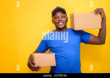 Un addetto alle consegne africano o un addetto alla spedizione che indossa una camicia blu, scatole per il trasporto e cappuccio per il viso Foto Stock