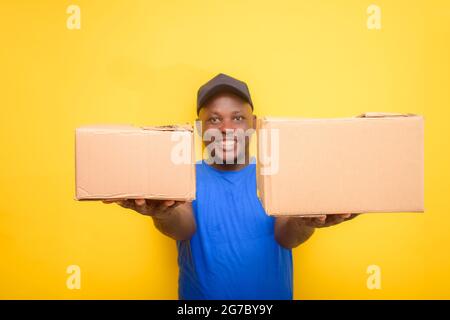 Un addetto alle consegne africano o un addetto alla spedizione che indossa una camicia blu, scatole per il trasporto e cappuccio per il viso Foto Stock