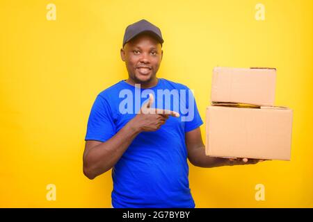 Un uomo di spedizione africano con cappuccio e che punta alle scatole che sta portando sulla sua spalla Foto Stock