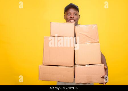 Un addetto alle consegne africano o un addetto alla spedizione che indossa una camicia blu, scatole per il trasporto e cappuccio per il viso Foto Stock