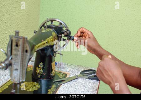 Un'industriosa sarto femminile africana, stilista di moda o creatrice di abiti, che fa abiti eleganti e alla moda con macchina da cucire in un'opera di sartoria Foto Stock