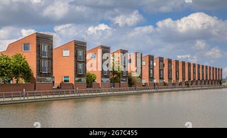 Staccato di moderne case famiglia adiacente al bordo di acqua nel sobborgo di Groningen Paesi Bassi Foto Stock