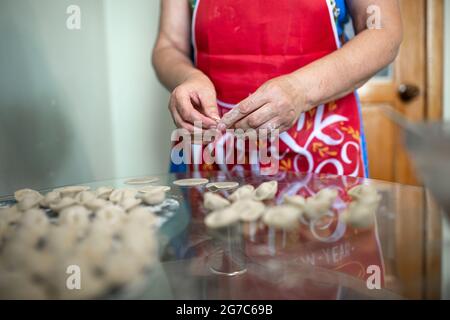 una donna in cucina prepara gnocchi di pasta e carne macinata. Foto Stock