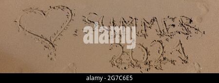 Inscription SUMMER 2021 is written on wet sand Stock Photo