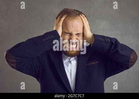 L'uomo stressato e infastidito copre le orecchie con le mani proteggendo da un forte rumore Foto Stock