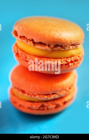 Macaron aromatizzati allo zafferano su sfondo blu. Realizzato da Les Macarons de PIM! Foto Stock
