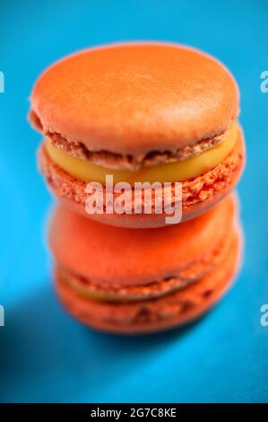 Macaron aromatizzati allo zafferano su sfondo blu. Realizzato da Les Macarons de PIM! Foto Stock