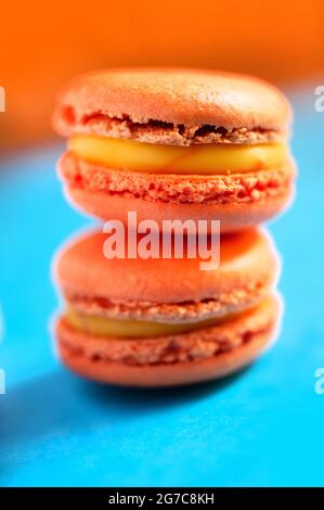 Macaron aromatizzati allo zafferano su sfondo blu e arancione. Realizzato da Les Macarons de PIM! Foto Stock