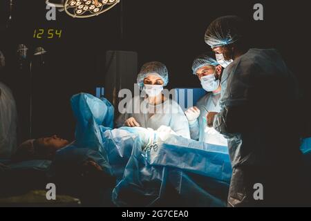 Il chirurgo senior nella sala operatoria, dove il paziente lo aspetta, e inizia l'operazione. Ospedale reale e moderno con autentica Foto Stock