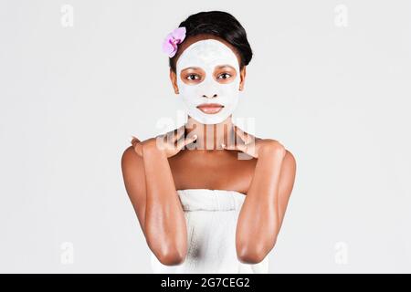 Giovane donna africana in Studio facendo la cura del corpo con rinfrescante maschera per il viso per la pelle giovane e bella e relax Foto Stock