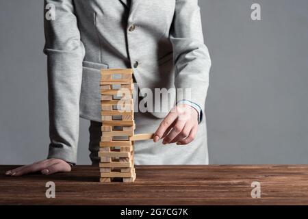 Uomo d'affari che rimuove il blocco di legno dalla torre Foto Stock