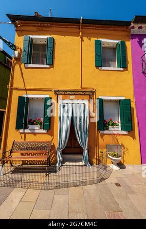 Vecchia piccola bella casa di colore luminoso (giallo e verde) nell'isola di Burano in una soleggiata giornata di primavera. Venezia, Veneto, Italia, Europa Foto Stock