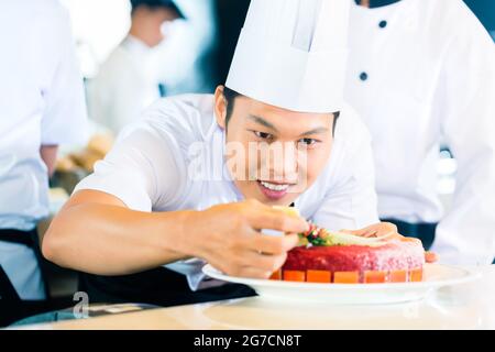 Uomo asiatico che indossa cappello e grembiule da chef sorride