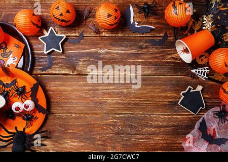 Halloween arancio ghirlanda sotto forma di zucca, ragni, scarafaggi, piatti e tazze su un vecchio tavolo di legno. Happy Halloween party background. Spazio libero, spazio di copia . Foto Stock