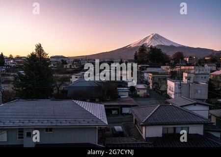 Vista dall'alba viola del Monte Fuji dalla città di Kawaguchiko in Giappone. Cima innevata della montagna più alta del Giappone da una città giapponese. Foto Stock