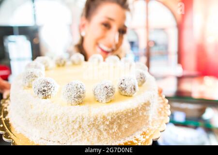 Pasticceria femmina presentando il vassoio della torta nel forno o pasticceria Foto Stock