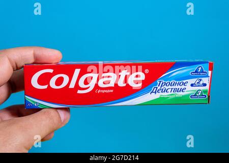 Tyumen, Russia-21 giugno 2021: Colgate Triple Action Extra Whitening dentifricio con calcio e fluoruro. Sfondo blu Foto Stock