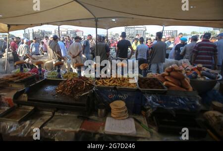 Gaza, Palestina. 13 luglio 2021. I palestinesi si riuniscono in un mercato del bestiame in preparazione alla prossima vacanza musulmana Eid al-Adha nella città di Dair al-Balah, nella striscia di Gaza sud. (Foto di Ahmed Zakot/SOPA Images/Sipa USA) Credit: Sipa USA/Alamy Live News Foto Stock