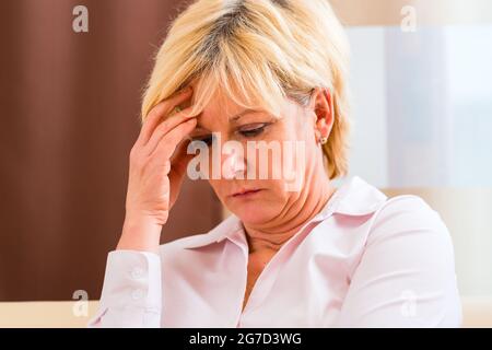 Vecchia donna tocca la fronte di mal di testa o emicrania Foto Stock