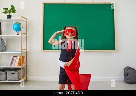 Ritorno a scuola. Supereroe positivo della studentessa in posizione di classe. Foto Stock