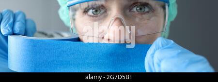 Donna medico sigilla la bocca con nastro blu Foto Stock