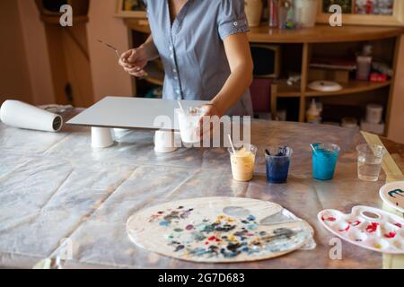 artista con l'aiuto di vernici crea un quadro moderno degli interni, lavora nella sua officina. Felicità e creatività. Design degli interni. Leisur domestico. Master Foto Stock