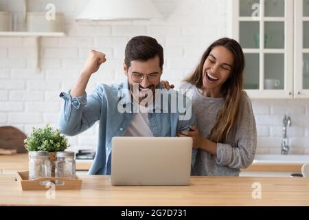 E-mail di lettura della famiglia da parte della banca sul portatile celebrare l'approvazione del prestito Foto Stock