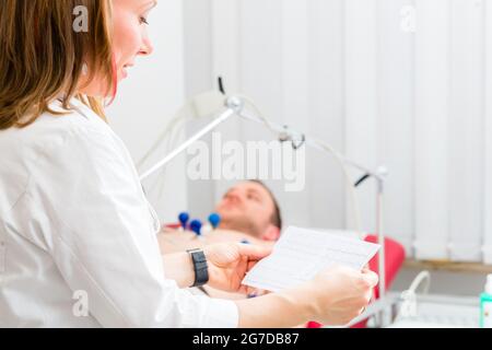 Medico donna analizzando elettrocardiogramma ECG del paziente in ospedale Foto Stock