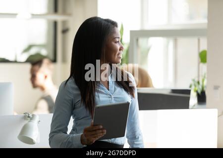 Felice giovane donna d'affari pensierosa che guarda la finestra Foto Stock