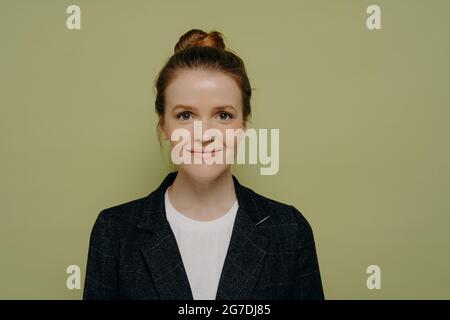 Studio ritratto di sorridente bella giovane donna con i capelli in panino Foto Stock