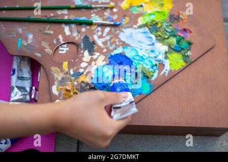 Palette con pitture e pennelli multicolore, foto di pittura femminile Foto Stock