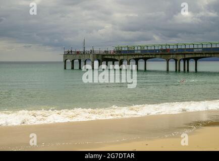 Boscombe, Bournemouth, Dorset, Regno Unito, 13 luglio 2021, Regno Unito Meteo: Nuvoloso ma caldo nel pomeriggio sulla costa sud come l'estate comincia a fare un ritorno. Un mare che simmer poteri lungo mentre la gente si rilassa sul molo, un po 'di pesca, all'inizio di quello che si prevede di diventare un lungo secco e forse caldo incantesimo di tempo. Credit: Paul Biggins/Alamy Live News Foto Stock