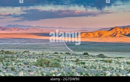 Strada sterrata che attraversa la valle di Dugway, ruscelli virga di pioggia evaporante sotto le nuvole, alba, da Pony Express Trail, Great Basin, Utah, USA Foto Stock