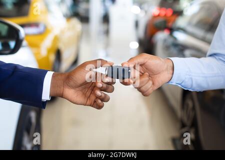 Cliente Black Male che prende le chiavi dell'automobile dal venditore nel centro della concessionaria, Closeup Foto Stock