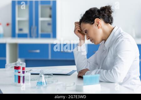 Vista laterale di uno scienziato afro-americano sconvolto che guarda i piatti di Petri in laboratorio Foto Stock