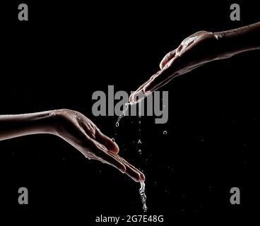 Mano dell'uomo africano che interagisce con l'acqua e sfondo nero. Foto Stock