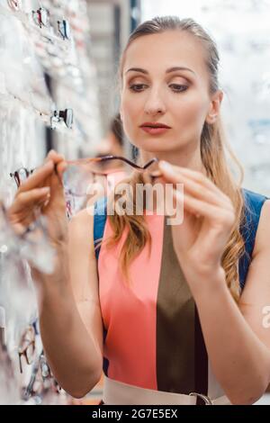 Donna shopping occhiali in all'ottico optometrista store scegliendo tra i modelli Foto Stock