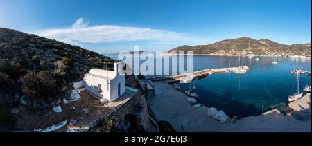 Isola di Sifnos, vista sul drone aereo di Platis gialos. Grecia Cicladi. Piccola chiesa su una collina, barche ormeggiate al porto turistico, calmo Mar Egeo, cielo blu backgro Foto Stock