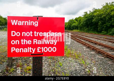 segnale di avvertimento che vieta la trasgressione e la sanzione finanziaria per le passeggiate sulle linee ferroviarie. Foto Stock