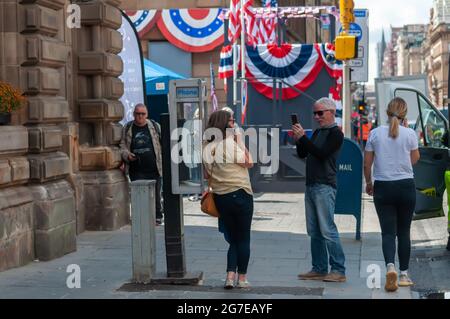 Glasgow, Scozia, Regno Unito. 13 luglio 2021. Durante le riprese di Indiana Jones e del film Dial of Destiny nel centro della città, i membri del pubblico scattano una foto utilizzando una cabina telefonica americana. Credito: SKULLY/Alamy Live News Foto Stock