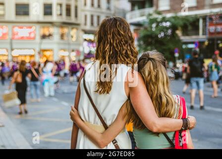 VALENCIA, SPAGNA - 30 giu 2021: Vista da dietro di Madre e figlia abbraccio a Gay Pride marzo con femministe in strada in background Foto Stock