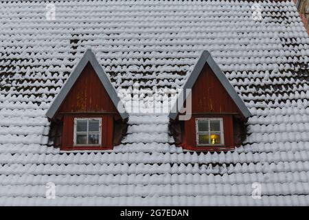 Vecchio tetto dell'edificio con finestre coperte di neve in inverno Moody giorno. Città vecchia Tallinn, Estonia Foto Stock