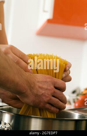 L'uomo - solo le mani da vedere - sta mescolando la cottura della pasta in acqua calda in una pentola Foto Stock