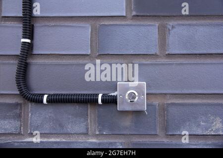 Pulsante di chiamata in una custodia in acciaio su uno sfondo a parete in mattoni Foto Stock