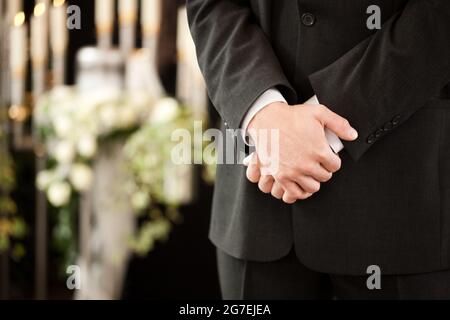 Religione, morte e dolore - undertaker ai funerali in piedi davanti o urna Foto Stock