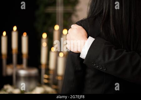 Religione, morte e dolore - coppia a funerali consolarsi l'un l'altro in vista della perdita Foto Stock