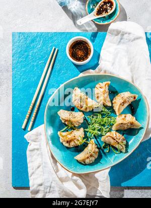 Gnocchi gyoza asiatici su una piastra blu. Foto Stock